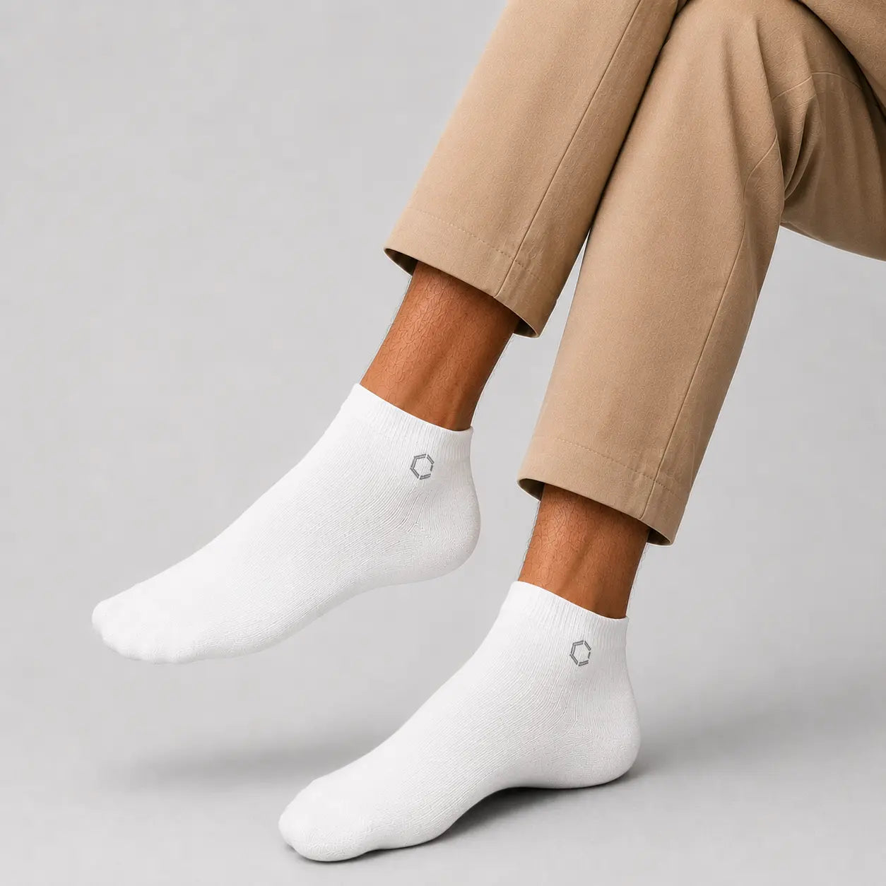 White ankle socks worn with beige pants on a gray background